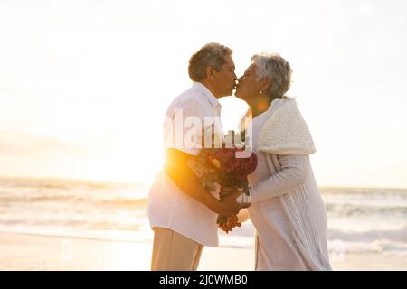 Side view of senior multiracial couple kissing each other during wedding ceremony at beach Stock Photo
