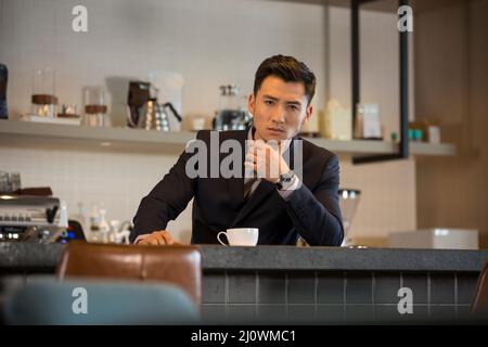 Successful Chinese business person drinks coffee in a Cafe Stock Photo