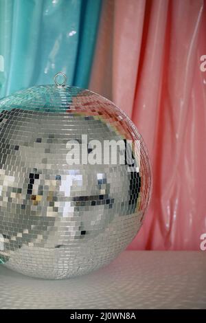 Large shiny reflective mirror silver sparkling nightlife disco ball against color background Stock Photo