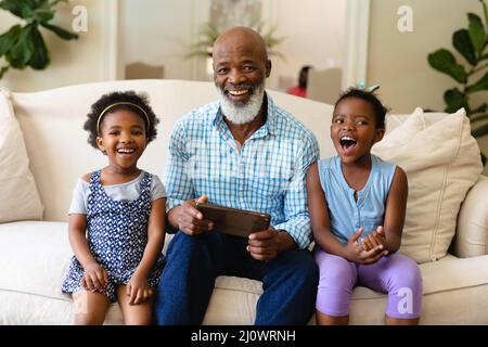 African american grandfather and his two granddaughters with digital tablet smiling at home Stock Photo
