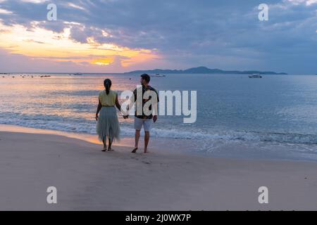 Sunset on Cosy Beach Pattaya Thailand , couple man and woman walking on the beach during sunset in Pattaya Thailand Stock Photo