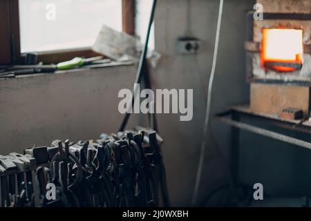 Blacksmith forge oven with hot flame. Smith heating iron piece of steel in fire of red-hot forge Stock Photo
