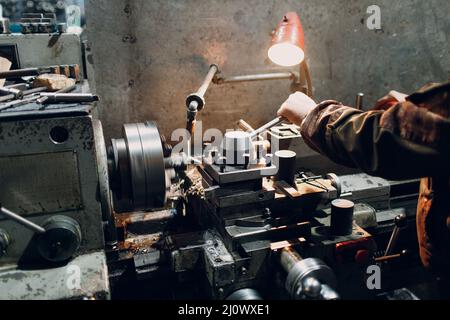 Turner worker working on old lathe machine at factory. Stock Photo