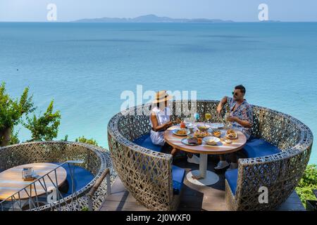 Couple having lunch at an restaurant looking out over the ocean of Pattaya Thailand, man and woman having dinner in restaurant b Stock Photo