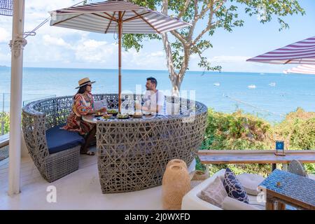 Couple having lunch at an restaurant looking out over the ocean of Pattaya Thailand, man and woman having dinner in restaurant b Stock Photo