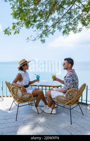 Couple having lunch at an restaurant looking out over the ocean of Pattaya Thailand, man and woman having dinner in restaurant b Stock Photo