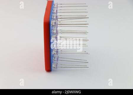 Side view of 3D printed LED jig with light-emitting diodes attached to the slots with the view of led pins arranged in order on white background Stock Photo