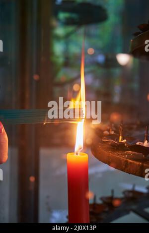 A bunch of aroma sticks are lit from a candle burning in a candlestick in a Japanese temple. Japan Stock Photo