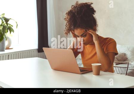 Frustrated African descent young woman in front of laptop at home, receiving e-mail with bad news Stock Photo