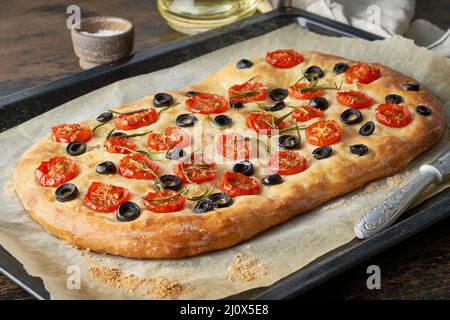 Focaccia, pizza, italian flat bread with tomatoes, olives and rosemary on tray Stock Photo