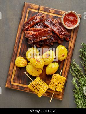 Spicy barbecue pork ribs, corn ears and crushed smashed potatoes. Slow cooking recipe Stock Photo