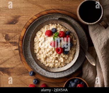 Oatmeal rustic porridge with blueberry, raspberries in ceramic vintage bowl, dash diet with berries Stock Photo