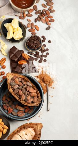 Cacao beans and powder, cacao butter and chopped chocolate on a white background, top view. Stock Photo