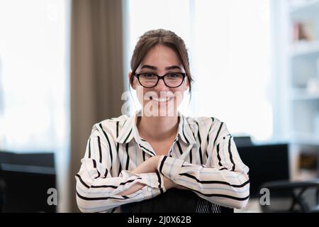 Portrait of businesswoman in casual clothes with glasses at modern startup open plan office interior. Selective focus Stock Photo