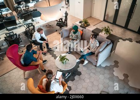 Top view photo of Multiethnic startup business team having brainstorming in relaxation area of modern office interior working on Stock Photo