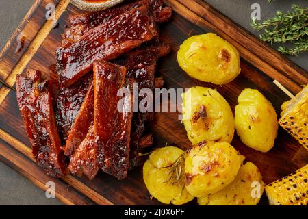 Spicy barbecue pork ribs, corn ears and crushed smashed potatoes. Slow cooking recipe. Stock Photo