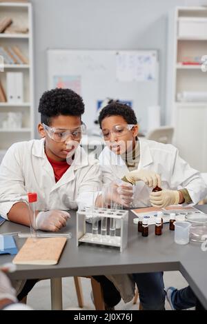 Vertican portrait of two curious African American children watching science experiments in chemistry lab at school Stock Photo
