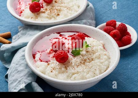 Rice pudding. French milk rice dessert with raspberries, blueberries. Dark background, side view Stock Photo