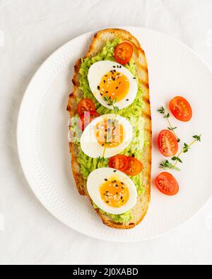 Avocado toast with toasted bread soft-boiled eggs with tomatoes Stock Photo
