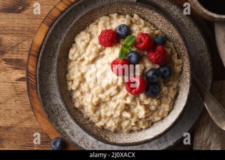 Oatmeal rustic porridge with blueberry, raspberries in ceramic vintage bowl, dash diet with berries Stock Photo