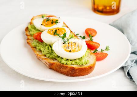 Avocado toast with toasted bread soft-boiled eggs with tomatoes Stock Photo