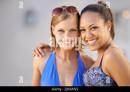 Enjoying the perfect girls getaway. Cropped view of two young woman in swimsuits smiling together. Stock Photo