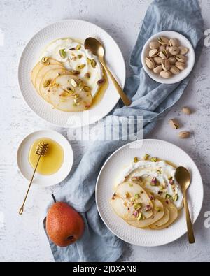 Ricotta with pears, pistachios and honey or maple syrup on white plate Stock Photo