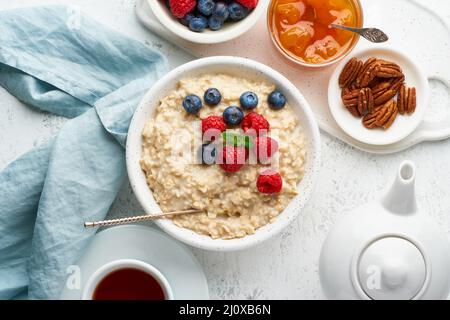 Oatmeal porridge with blueberry, raspberries, jam and nuts, top view. Breakfast with berries Stock Photo