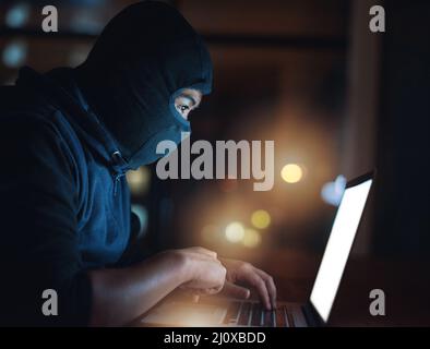 How secure is your system really. Shot of a hacker using a laptop in the dark. Stock Photo