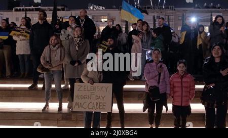 Tel Aviv, Israel. 20th Mar, 2022. Demonstrators sing the 'State Anthem of Ukraine,' the national anthem of Ukraine, as they gather to watch a video address by Ukraine’s President Volodymyr Zelensky to the Israeli parliament broadcasted at Habima Square on March 20, 2022 in Tel Aviv, Israel. Zelensky asked Israel to impose sanctions on Russia and to help Ukraine, recalling Nazi Germany and comparing its actions to the current situation. Credit: Eddie Gerald/Alamy Live News Stock Photo