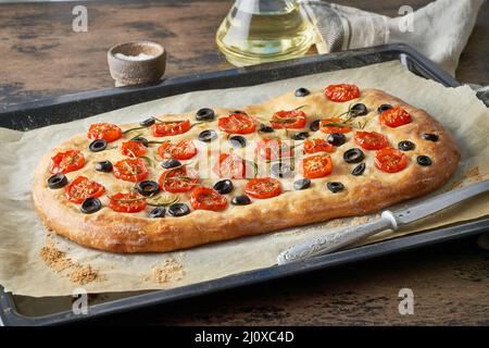 Focaccia, pizza, italian flat bread with tomatoes, olives and rosemary on tray Stock Photo