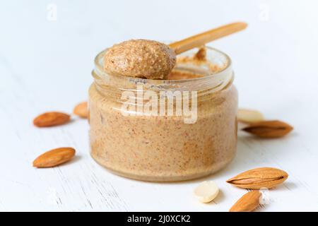 Nut butter, crunchy and stir, white wooden table, glass jar, side view, close up Stock Photo