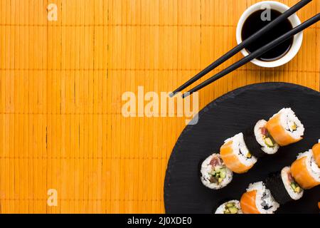 Flat lay sushi arrangement orange bamboo mat Stock Photo