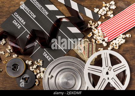 Negatives stripes with clapperboard film reels tickets popcorn wooden desk Stock Photo