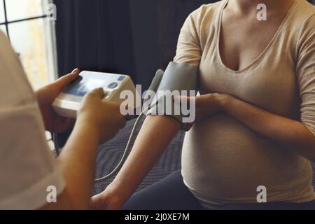 Hypertension in pregnancy. Doctor measuring blood pressure of pregnant woman Stock Photo