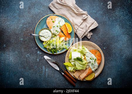 Healthy food meal grilled salmon steaks with dill sauce and salad leafs on two plates Stock Photo