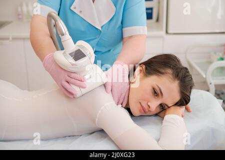 Woman receiving treatment for cellulite. Slimming vacuum massage machine.  Stock Photo by EkaterinaPereslavtseva