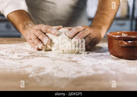 Male baker kneading dough flour wooden table Stock Photo