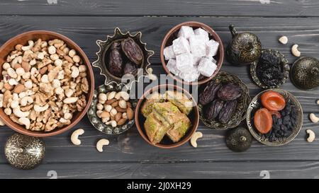 Lukum dates dried fruits baklava nuts earthen metallic bowl wooden desk. High quality beautiful photo concept Stock Photo