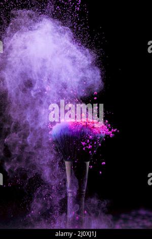 Vibrant burst makeup powder with brush dark background. High quality beautiful photo concept Stock Photo