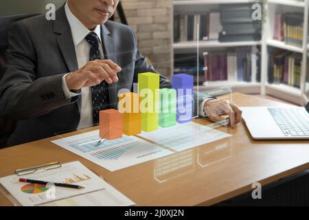 Asian businessman interacting with augmented reality three-dimensional bar graph while analyzing a return on investment and business performance Stock Photo