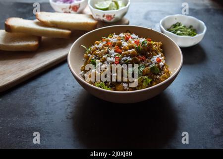 Indian street food ghugni or dried yellow peas cooked with spices served in a bowl on a dark background. Top view Stock Photo