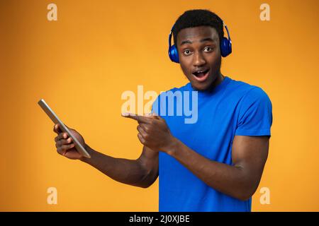 Smiling african guy using digital tablet over yellow background Stock Photo