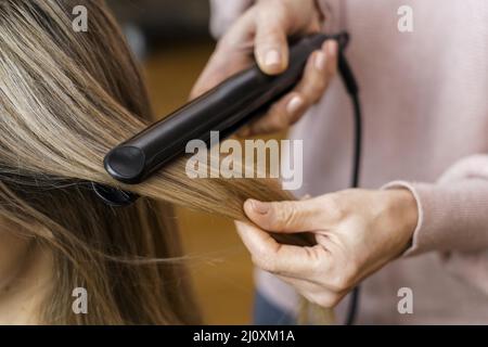 Woman getting her hair straightened home. High quality beautiful photo concept Stock Photo