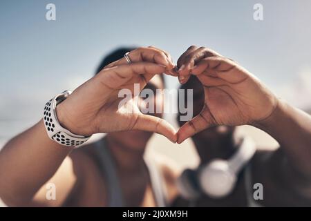 Working out together has strengthened our bond. Shot of two sporty young women forming a heart shape with their hands. Stock Photo