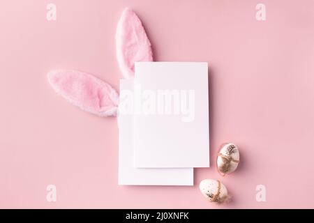 Easter mockup with decorative rabbit ears and eggs, poster on pink background Stock Photo