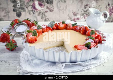 Traditional German cheesecake with strawberry fruits served as close-up in a backing form on a wooden table Stock Photo