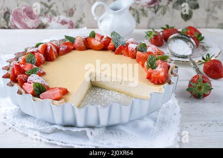 Traditional German cheesecake with strawberry fruits served as close-up in a backing form on a wooden table Stock Photo