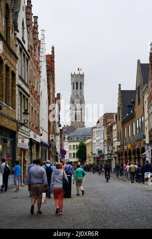 Walking along Steenstraat with the Belfry of Bruges in front. Stock Photo