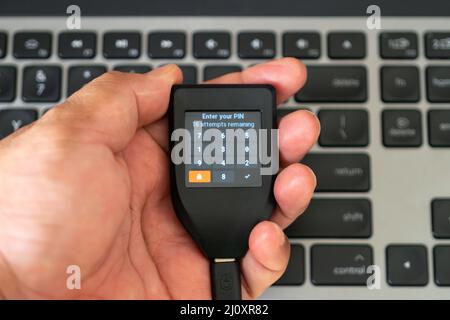 Holding hardware wallet on hand and typing pin code Stock Photo